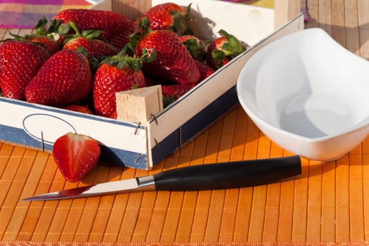 Strawberries in wooden box with peel and knife