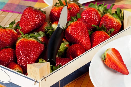 Strawberries in wooden box with peel and knife