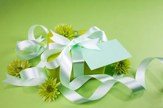 Gift box with flowers on green background