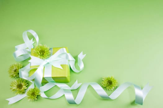 Gift box with flowers on green background