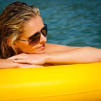 Summer woman daydreaming lying on yellow floating mattress close-up