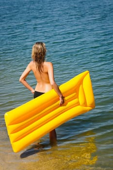 Summer woman by sea water with floating mattress looking forward