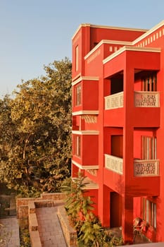 Portrait of generic modern architeture of 3 storey concrete block, brightly colored, blue sky and garden layout