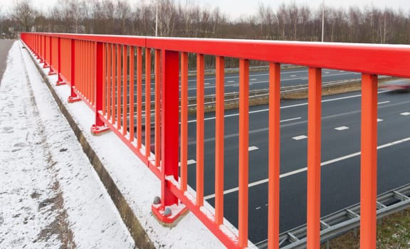 red handrail as part of a footbridge over a highway