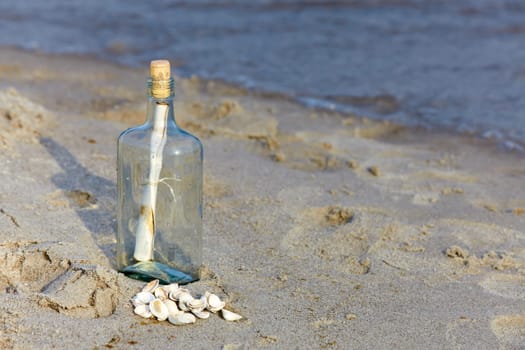 Message in a bottle with letter on the sandy beach