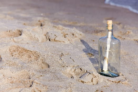 Message in a bottle with letter on the sandy beach