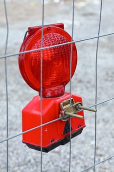Red construction site lighting attached to a construction fence