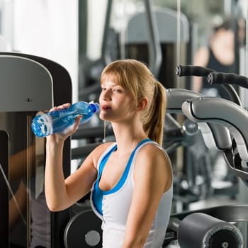 Young woman relax at the gym sitting on fitness machine