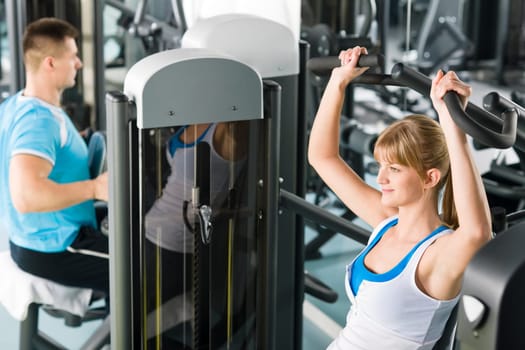 Active man and woman at fitness center exercise on machine