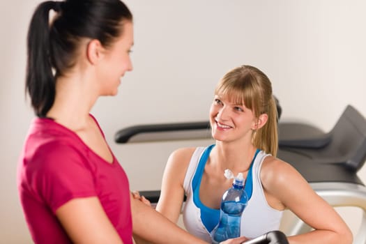 Young woman friends exercising in fitness center on treadmill machine