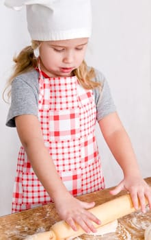 the girl in the hat chef rolls the dough