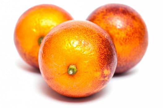 Three blood oranges against a white background