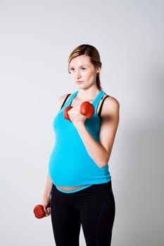 Pregnant woman exercising the bicep muscles with dumbbells