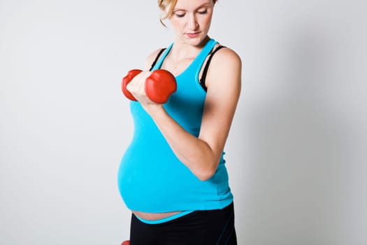 Pregnant woman exercising the bicep muscles with dumbbells