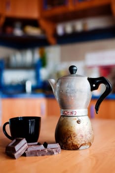 An image of coffee maker with cup and chokolate