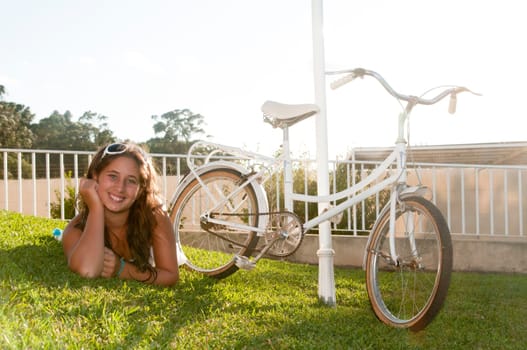 Beautiful young girl with big hat and bicycle in high-keys