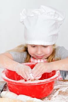 girl in chef&#039 s hat the breaks the egg in a bowl