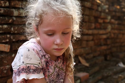 sad little girl on the background of an old brick wall