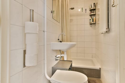 a bathroom with a toilet, sink and shower stall in the same room on the left side of the photo