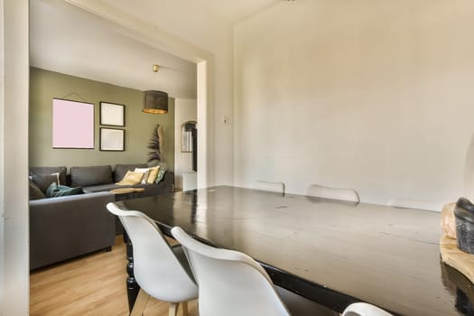 a dining room with white chairs and a black table in the center of the room is an open door that leads to a living