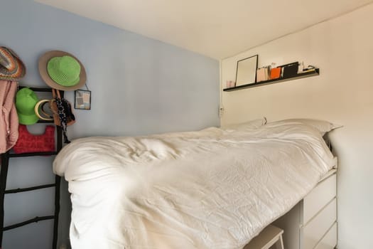 a small room with a bed, hat and other items hanging on the wall behind it is a ladder that has been used for