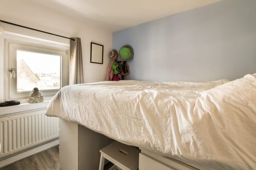 a woman standing on the edge of a bed in a room with blue walls and wooden floors, while she looks at her reflection