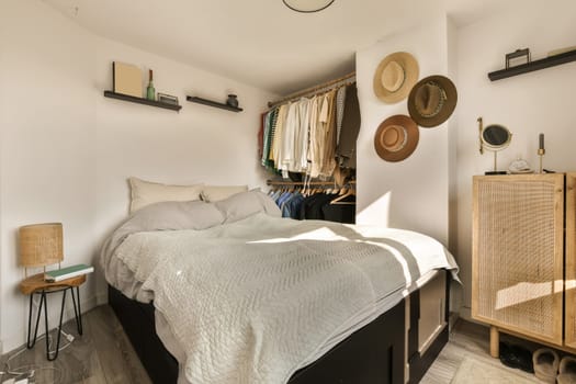a bedroom with a bed, dresser and hat on the wall behind it is a shelf that has clothes hanging