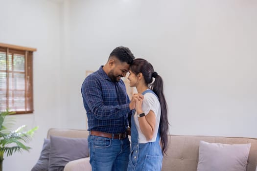 Happy love indian couple dance, holding hands, having fun together at home on weekend, romantic relationship concept.