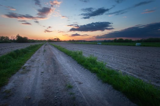 Dirt road and plowed fields with evening sky, view on a spring day, Nowiny, Poland
