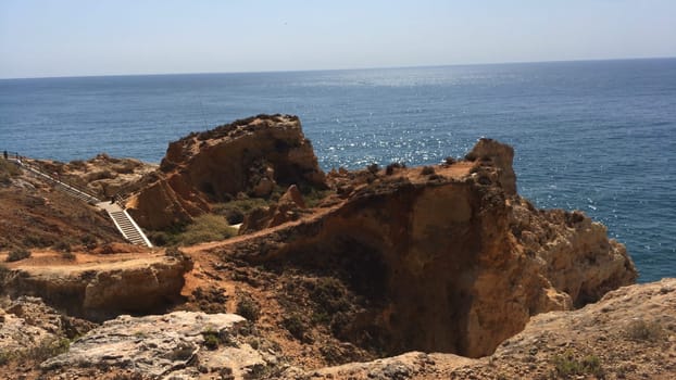 Wooden pathway built on a rocky coastline near Carvoeiro town, Lagoa, Algarve - Portugal.