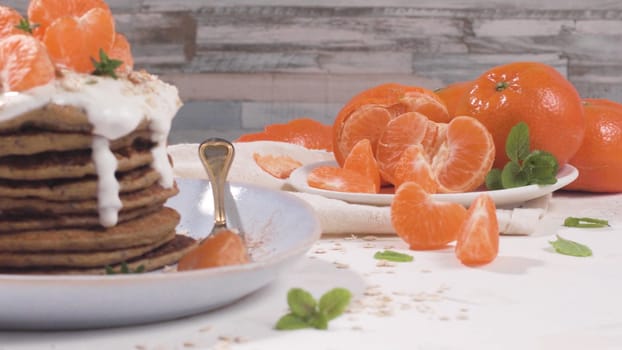 Pancakes with yogurt and tangerines on a light modern kitchen counter top with oat, thyme and mint leaves.