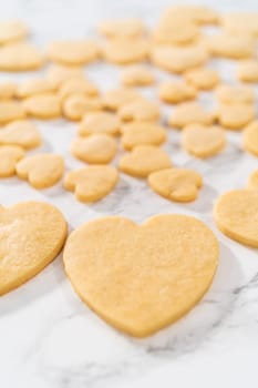 Decorating heart-shaped sugar cookies with pink and white royal icing for Valentine's Day.