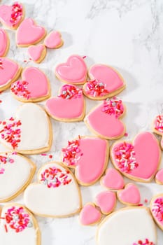 Decorating heart-shaped sugar cookies with pink and white royal icing for Valentine's Day.