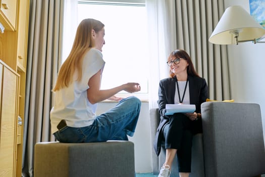 Female psychologist therapist working with young teen girl sitting in office. Teenage female student at therapy meeting with counselor. Psychology therapy psychotherapy youth mental health treatment