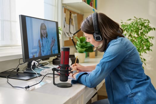 Young woman having a video conference with a doctor. Female patient sitting at table at home talking with general practitioner. Technology, medicine, online consultation, health care concept