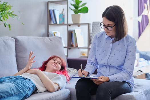 Psychologist helping teenage female, individual therapy in doctors office. Professional counselor listening teenager, girl lying on couch. Mental health, adolescence, psychology, psychiatry concept