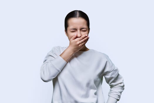 Teenage girl having toothache, on white studio background. Dental health, teenagers, young people concept