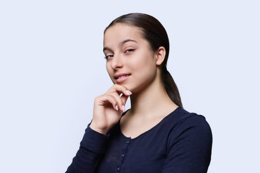 Portrait of teenager girl looking at camera on white studio background. Smiling teenage female 15, 16 years old. Adolescence, high school student, youth concept