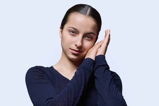 Young woman sleeping, holding hands near ear, sleeping gesture, looking at camera on white studio background. Body language, healthy sleep, beauty, lifestyle, youth students concept