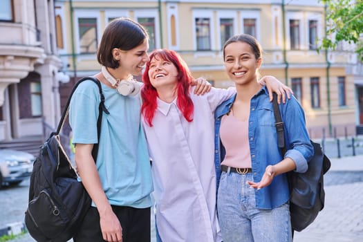 Happy smiling hugging teenage friends outdoor, on city street. Friendship, community, youth, lifestyle, leisure fun concept