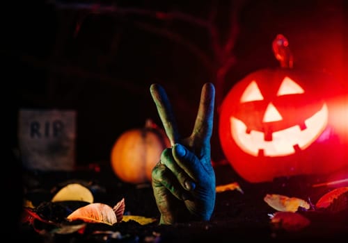Terrible zombie hand with peace sign from grave. V - victory gesture. Creepy moment from undead life. Halloween concept. Living nightmare comes to life. High quality