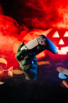 Zombie hand with joypad controller, wireless gamepad. Undead, halloween games sale. Terrifying scene from underground. Copy space. High quality