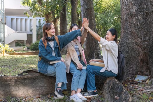 Group of cheerful Asian college students expressing happiness or friends Laughing together while sitting on campus.