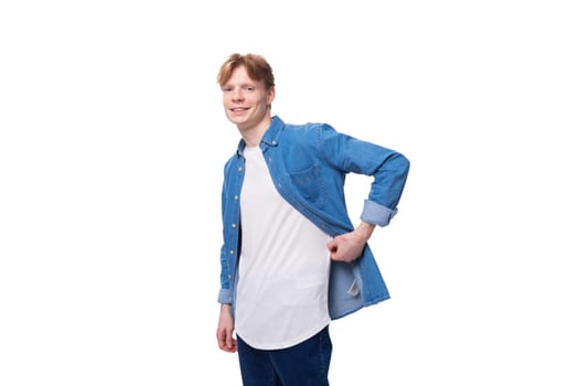 young caucasian red-haired man in a denim shirt over a white t-shirt posing fashionably.