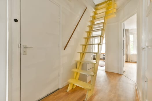 a yellow staircase in a white room with wood flooring and wooden stairs leading up to the second floor area