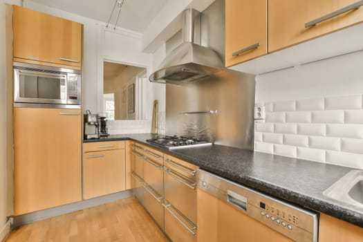 a modern kitchen with wood cabinets and stainless steel appliances in the photo is taken from the front door to the left