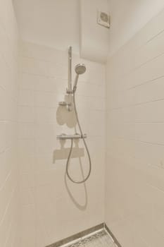 a shower stall in a tiled bathroom with white tiles on the walls, and a chrome hand rail attached to the wall