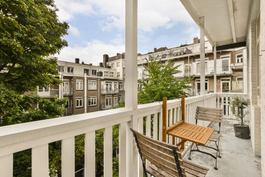 a wooden bench on a porch with trees and buildings in the background, taken from outside looking out to the street