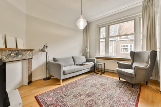 a living room with a couch, chair and fire place in the center of the room there is a rug on the floor