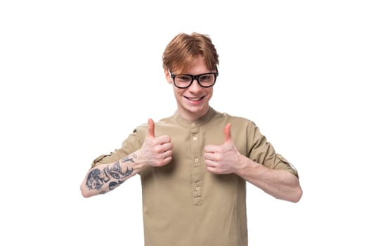 young cheerful optimist handsome man with copper hair with a tattoo on his arm is dressed in a khaki shirt.
